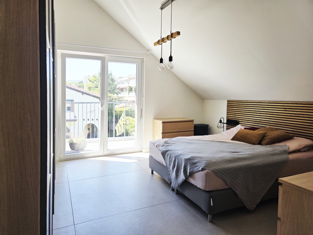 Chambre lumineuse ouverte sur le balcon par de grandes baies vitrées