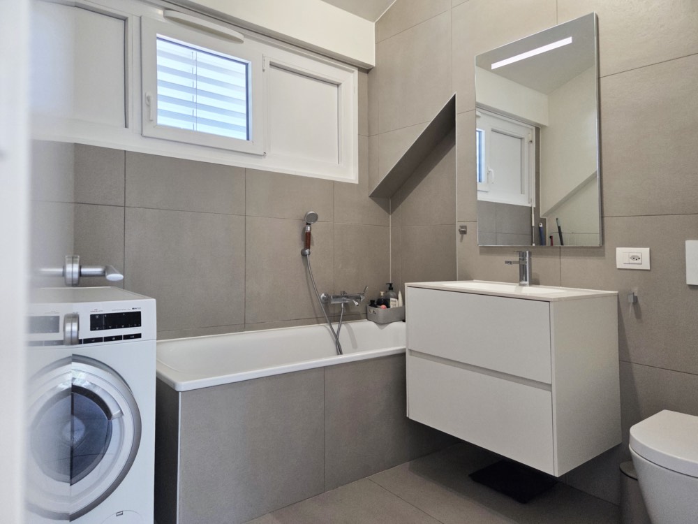 Salle de bains moderne avec baignoire, meuble vasque et lave-linge